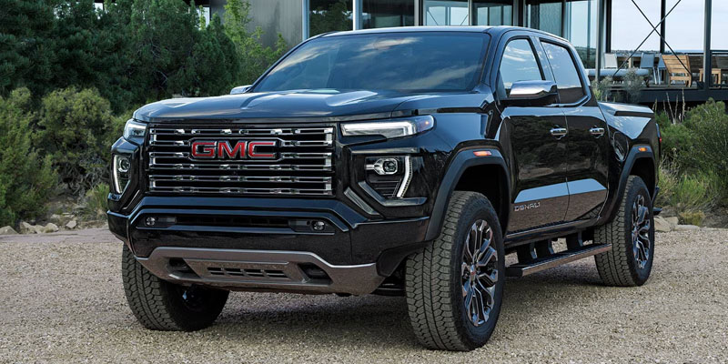 A black GMC Denali truck parked in an outdoor setting with trees in the background.
