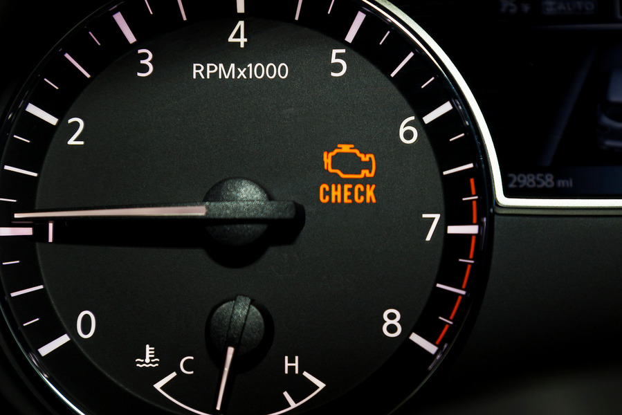 An orange check engine light illuminated on a car's tachometer dashboard gauge.