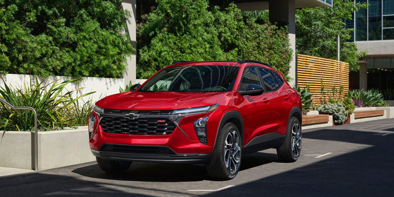 Red Chevrolet Trax SUV parked in a modern plaza.